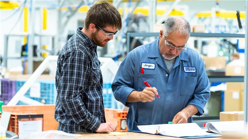 Two engineers reviewing technical drawings for a custom automated manufacturing machine